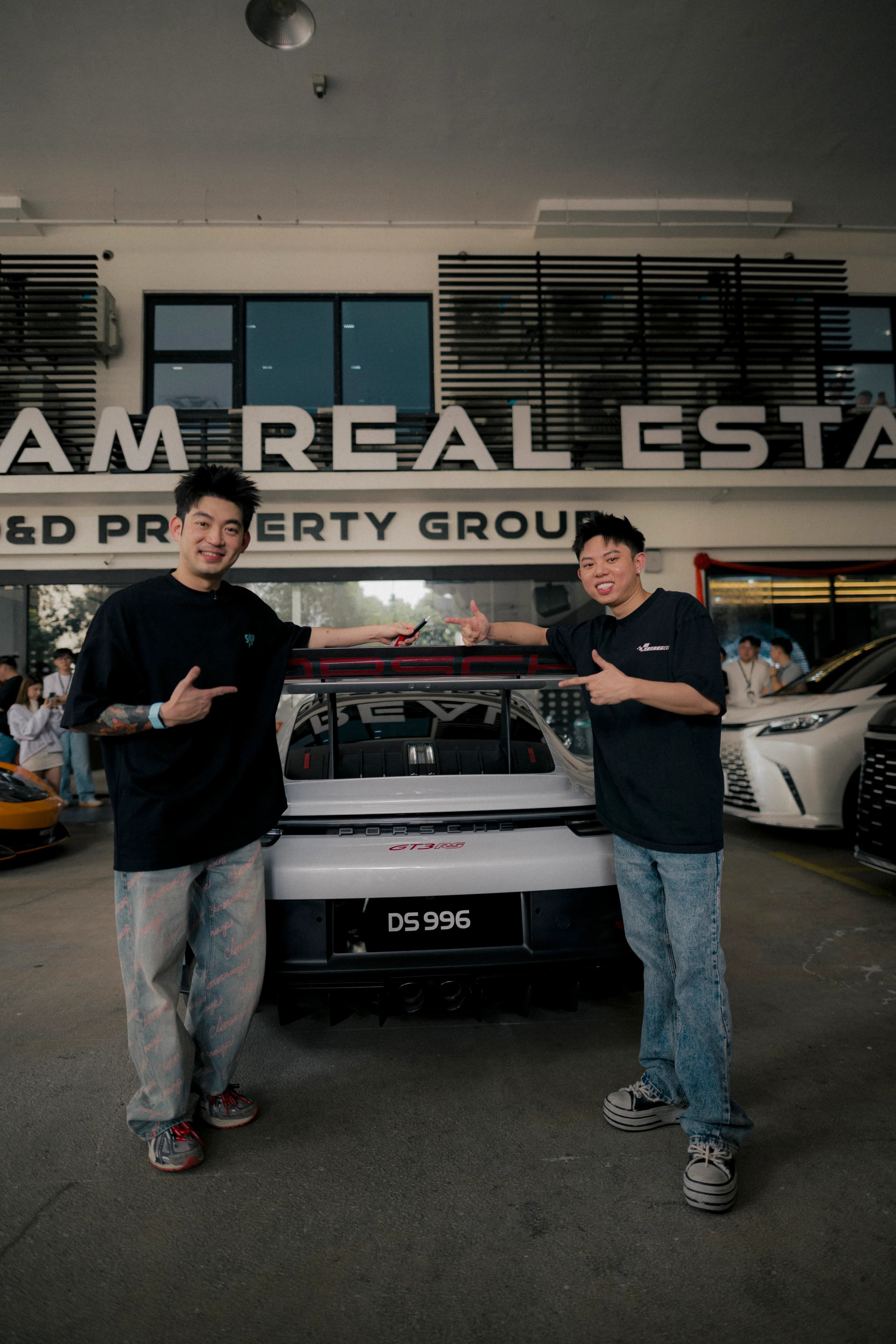 Two teammates pointing at the Porsche GT3 RS rear wing